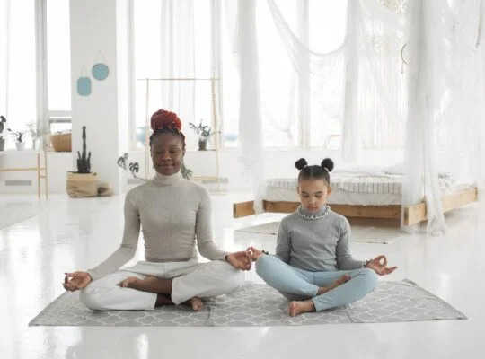 adorable african american kid with young mom practicing yoga in lotus pose